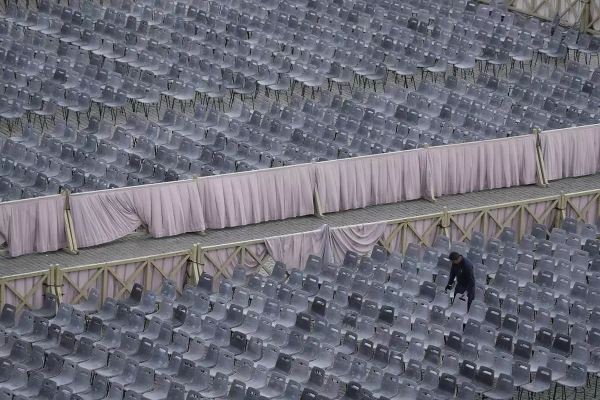 A worker adjusts chairs during the preparations in St. Peter's Square ahead of the arrival of the body of Pope Francis, who will lie in state at St. Peter's Basilica for three days, at the Vatican, Wednesday, April 23, 2025. (AP Photo/Gregorio Borgia)