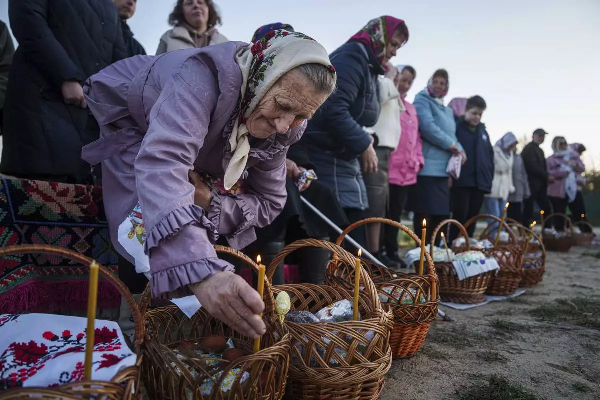 An elderly woman prepares her Easter baskets to be blessed during celebration of the Orthodox Easter in Krasne village, Ukraine, on Sunday, April 20, 2025. (AP Photo/Evgeniy Maloletka)