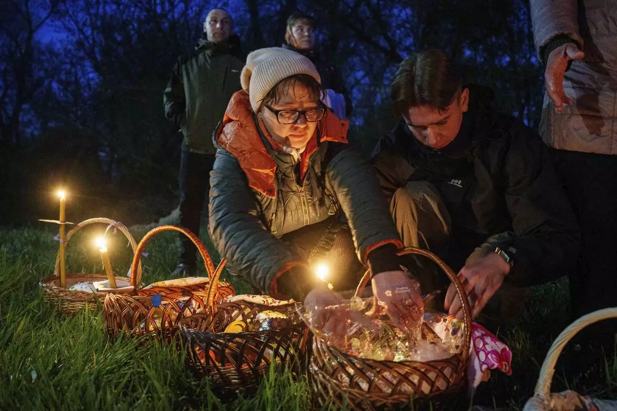 People prepare their Easter baskets to be blessed in front of a church destroyed in fighting between Russian and Ukrainian forces, during celebration of the Orthodox Easter in Lukashivka village, Ukraine, on Sunday, April 20, 2025. (AP Photo/Evgeniy Maloletka)