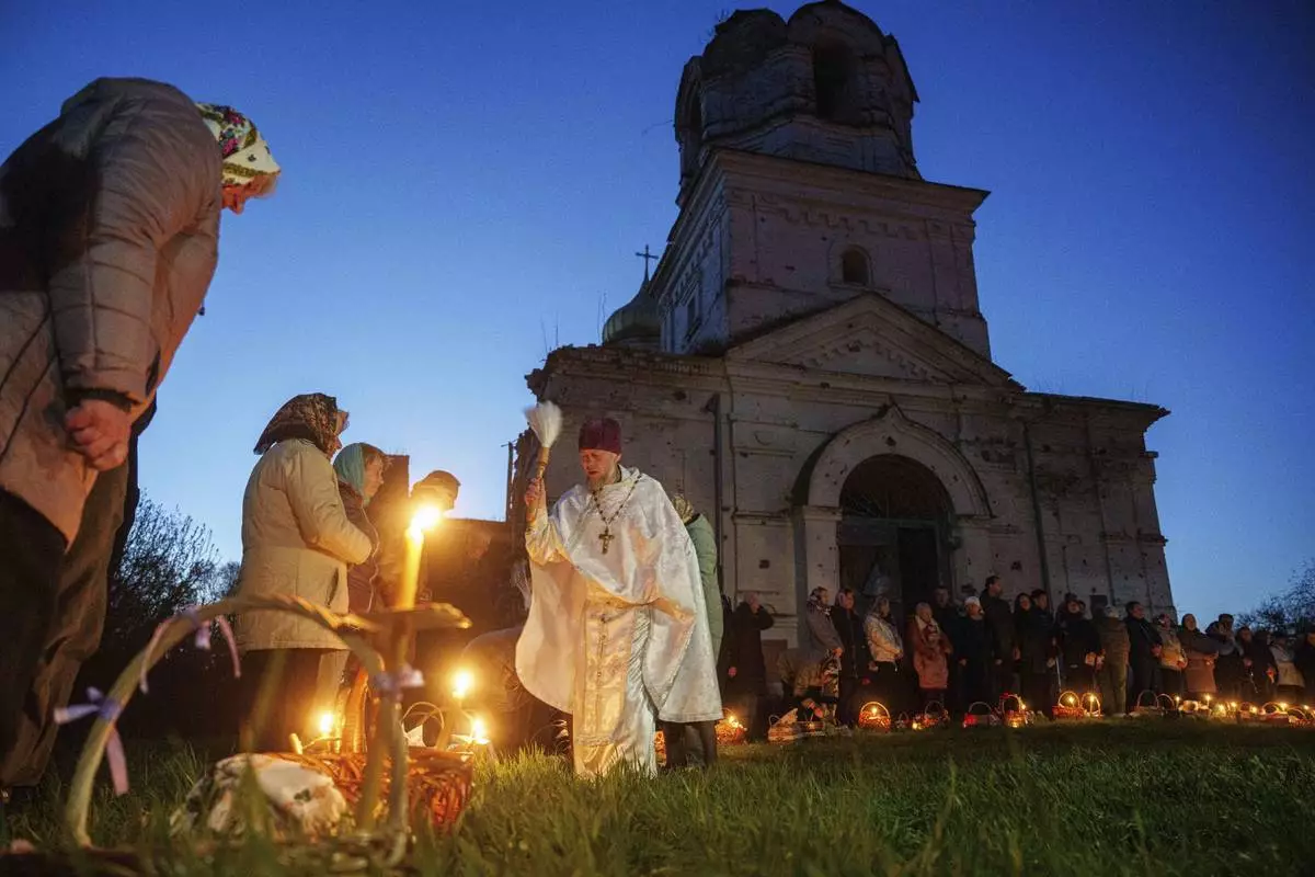 Priest Serhii Zezul blesses Easter baskets in front of a church destroyed in fighting between Russian and Ukrainian forces, during celebration of the Orthodox Easter in Lukashivka village, Ukraine, on Sunday, April 20, 2025. (AP Photo/Evgeniy Maloletka)
