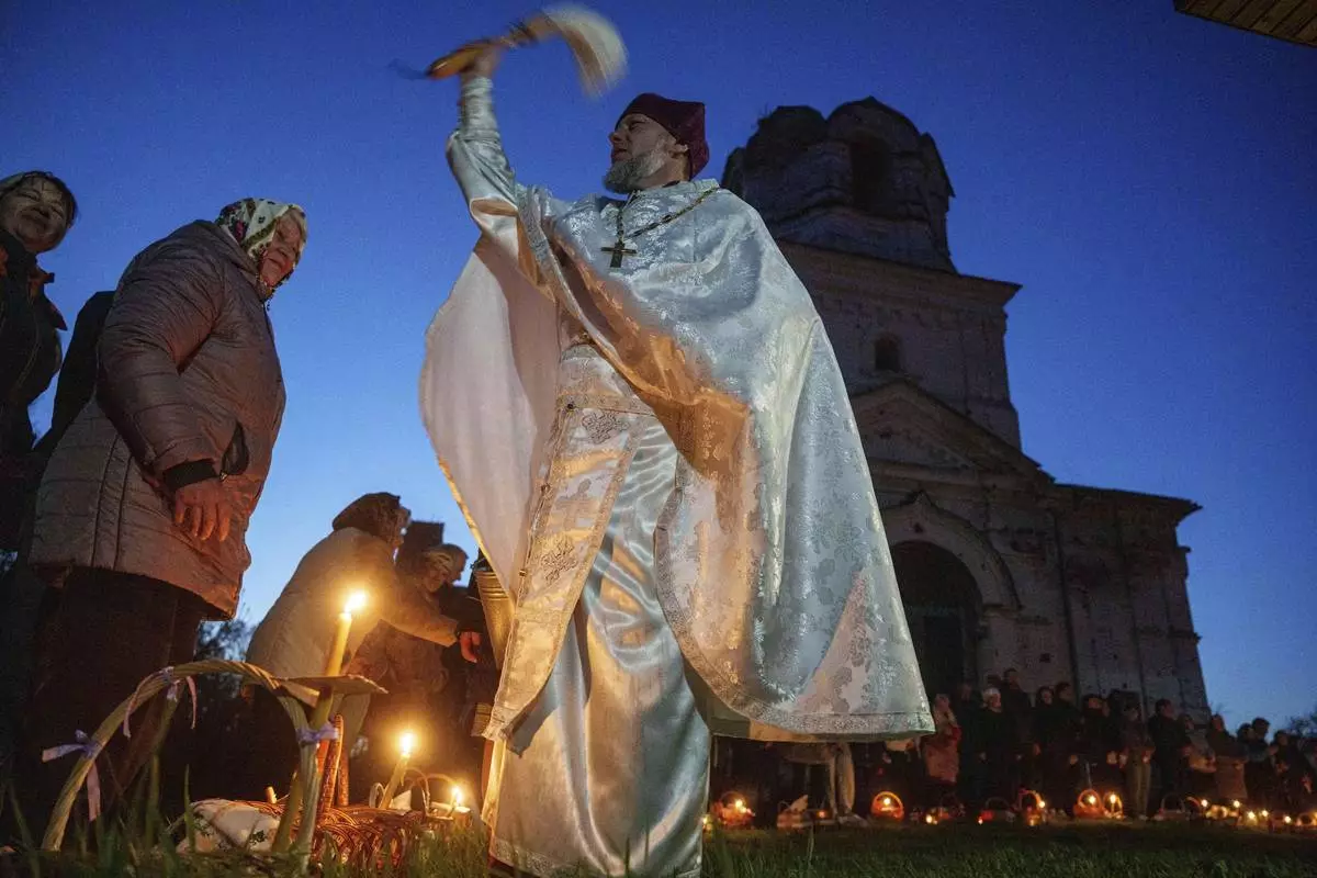 A priest Serhii Zezul blesses Easter baskets in front of a church destroyed in fighting between Russian and Ukrainian forces, during celebration of the Orthodox Easter in Lukashivka village, Ukraine, on Sunday, April 20, 2025. (AP Photo/Evgeniy Maloletka)
