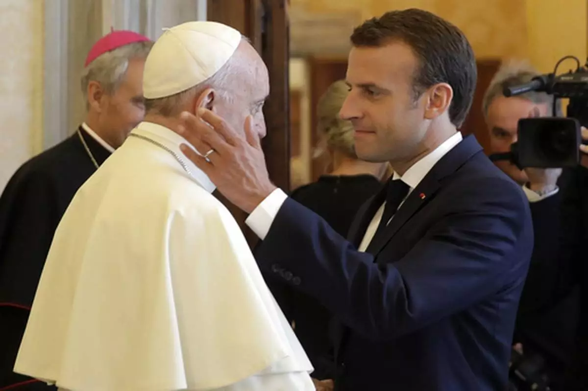 FILE - French President Emmanuel Macron, right, shakes hands with and goes to hug Pope Francis at the end of their private audience, at the Vatican, Tuesday, June 26, 2018. (Alessandra Tarantino/Pool Photo via AP, File)