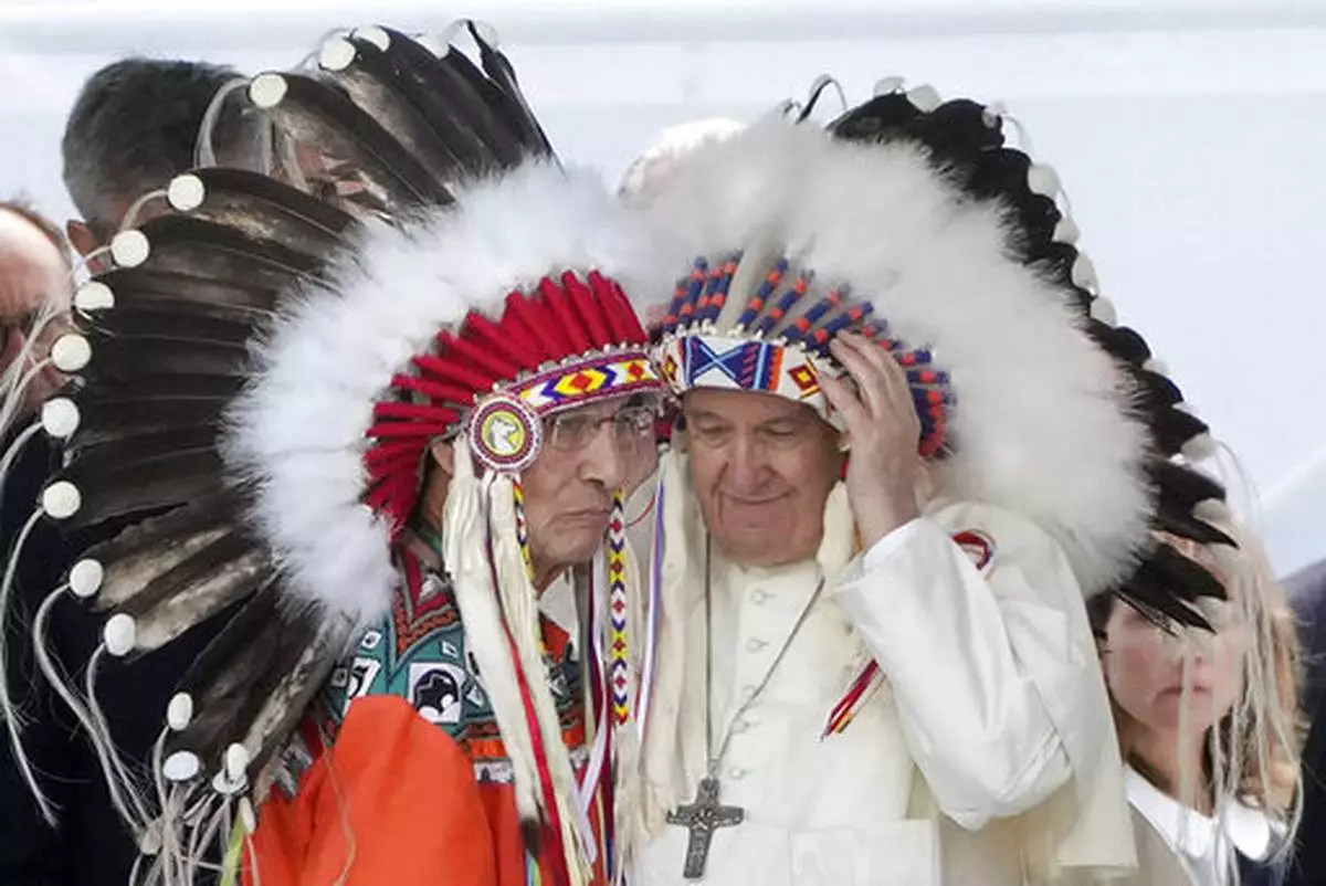 FILE - Pope Francis puts on an indigenous headdress during a meeting with Indigenous communities, including First Nations, Metis and Inuit, at Our Lady of Seven Sorrows Catholic Church in Maskwacis, near Edmonton, Canada, Monday, July 25, 2022. (AP Photo/Gregorio Borgia, File)