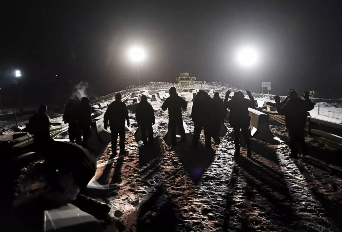 FILE - Military veterans walk onto a closed bridge to protest across from police protecting the Dakota Access oil pipeline site in Cannon Ball, N.D., Thursday, Dec. 1, 2016. (AP Photo/David Goldman, File)