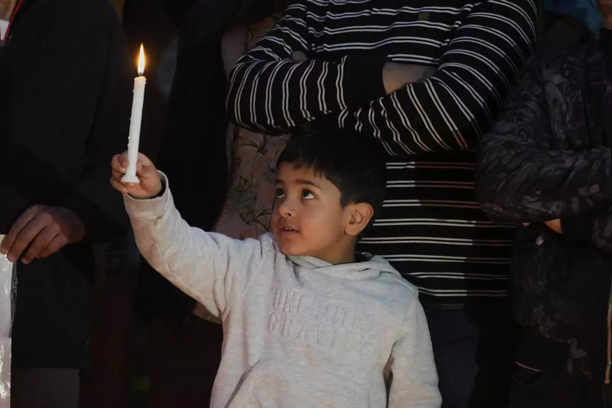 A child holds a candle during a candlelight protest in Srinagar, Indian controlled Kashmir, Wednesday, April 23, 2025, a day after an attack killed at least 26 people, most of them tourists. (AP Photo/Mukhtar Khan)