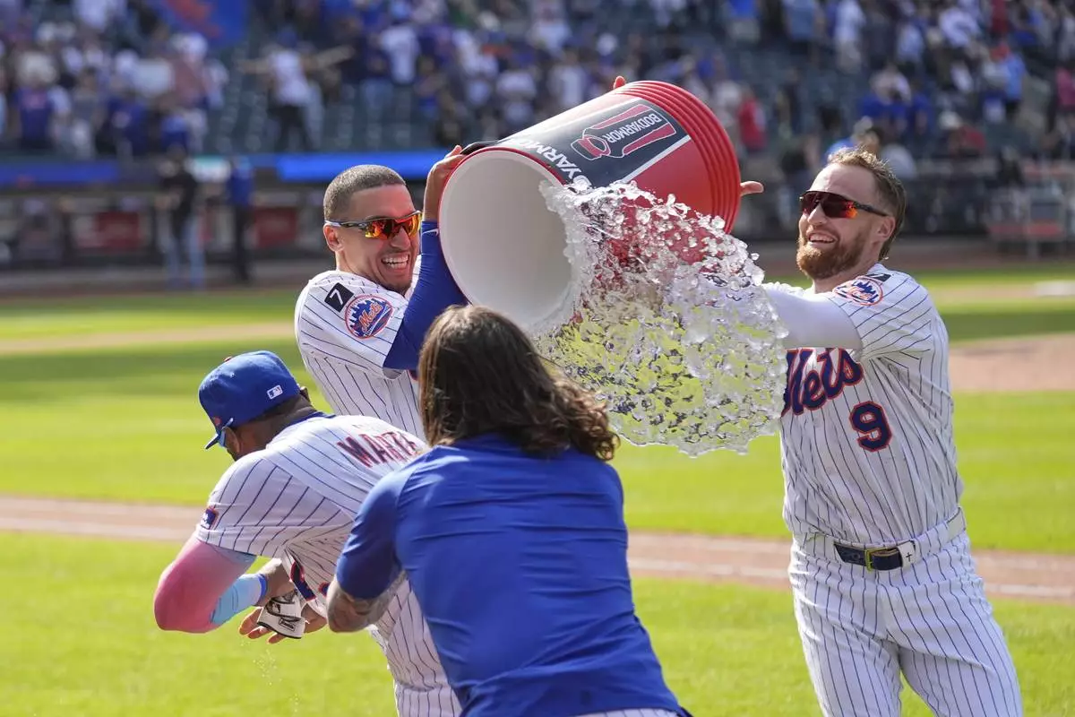 New York Mets' Tyrone Taylor, second from left, and Brandon Nimmo (9), right, try to douse Starling Marte, left, after he hit a walk off single during the tenth inning of a baseball game against the Philadelphia Phillies, Wednesday, April 23, 2025, in New York. (AP Photo/Seth Wenig)