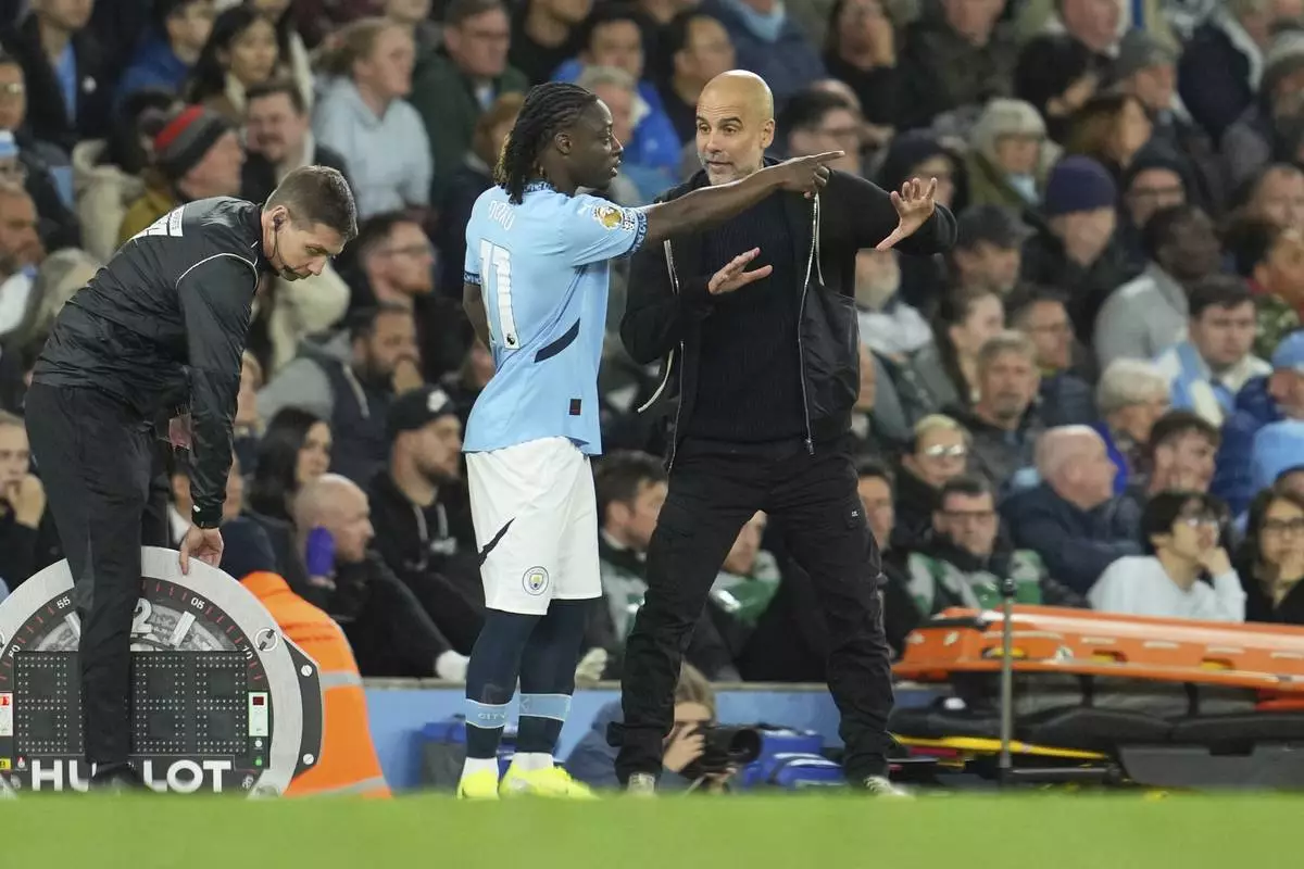 Manchester City's head coach Pep Guardiola talks with Manchester City's Jeremy Doku during the English Premier League soccer match between Manchester City and Aston Villa at Etihad stadium in Manchester, England, Tuesday, April 22, 2025. (AP Photo/Jon Super)