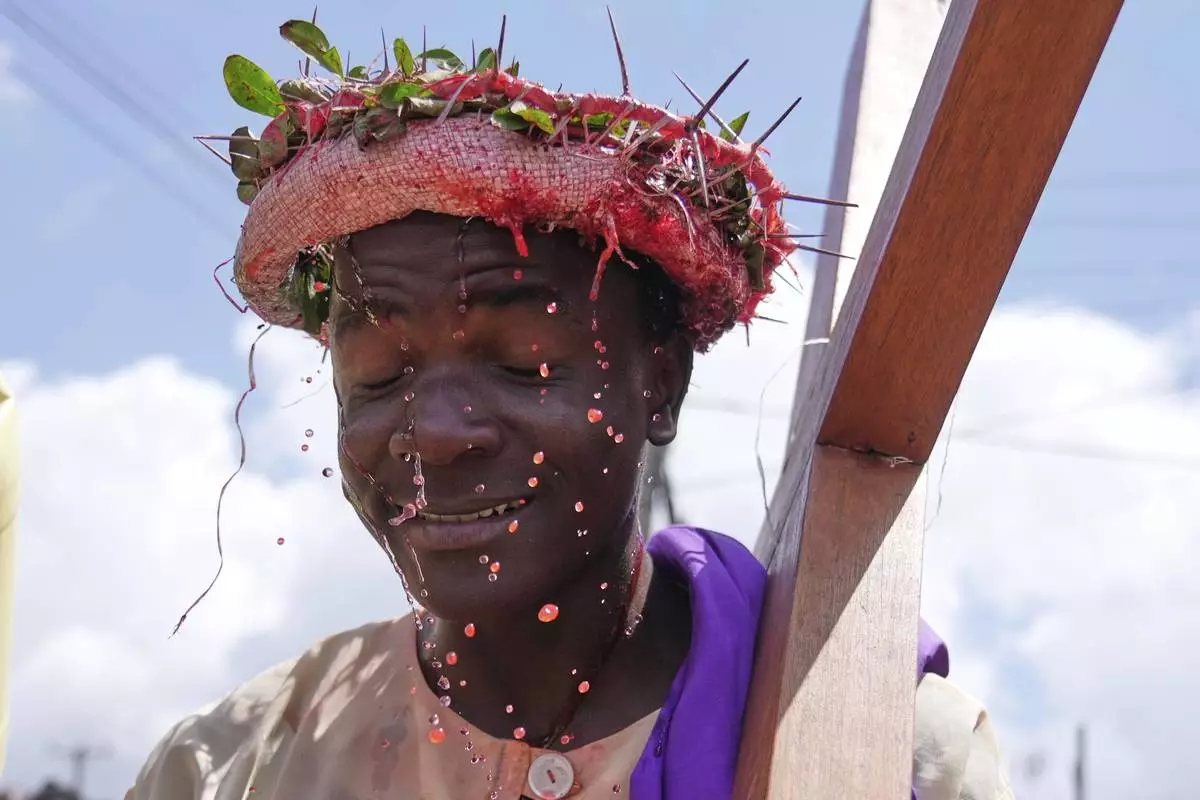 An actor portraying Jesus Christ carries a cross during a Way of the Cross reenactment during Holy Week celebrations in the Kibera informal settlement of Nairobi, Kenya, Friday, April 18, 2025. (AP Photo/Brian Inganga)