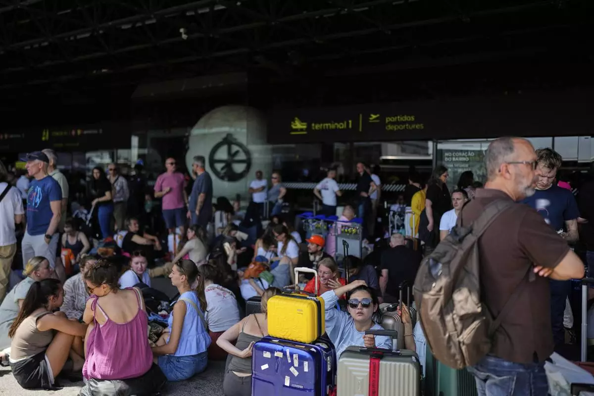 Passengers wait outside Lisbon Airport during a nationwide power outage in Lisbon, Monday, April 28, 2025. (AP Photo/Armando Franca)