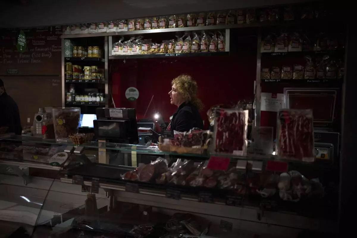 Vendors use their phone light to select and save some food, during a major power outage in Barcelona, Spain, Monday, April 28, 2025. (AP Photo/Emilio Morenatti)