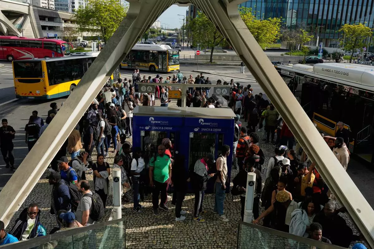 Passengers queue to catch buses at Oriente transportation hub during a nationwide power outage that stopped trains and subway in Lisbon, Monday, April 28, 2025. (AP Photo/Armando Franca)