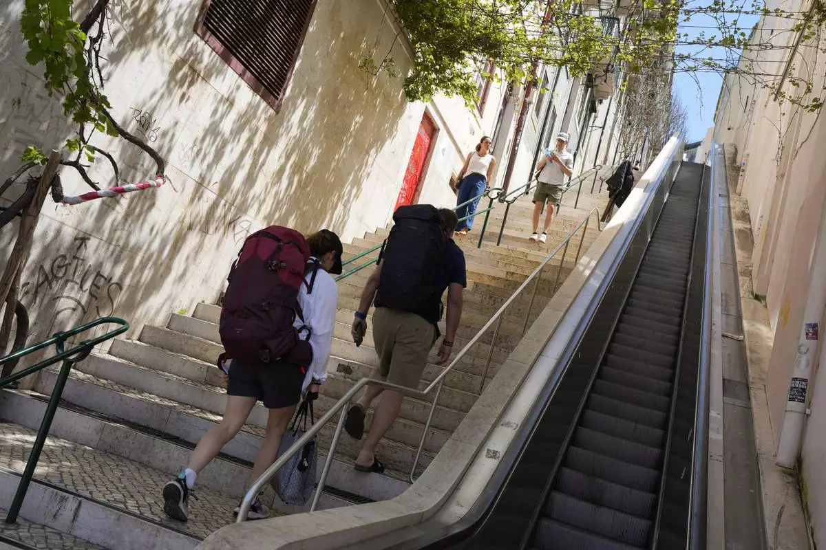 People climb stairs in Lisbon old centre after the escalator stopped working following a power outage, Monday, April 28, 2025. (AP Photo/Armando Franca)