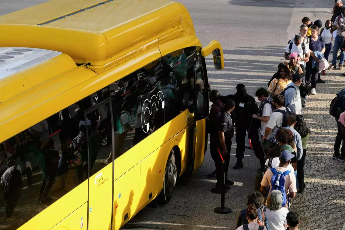 Private security controls passengers boarding buses at Oriente transportation hub during a nationwide power outage that stopped trains and subway in Lisbon, Monday, April 28, 2025. (AP Photo/Armando Franca)