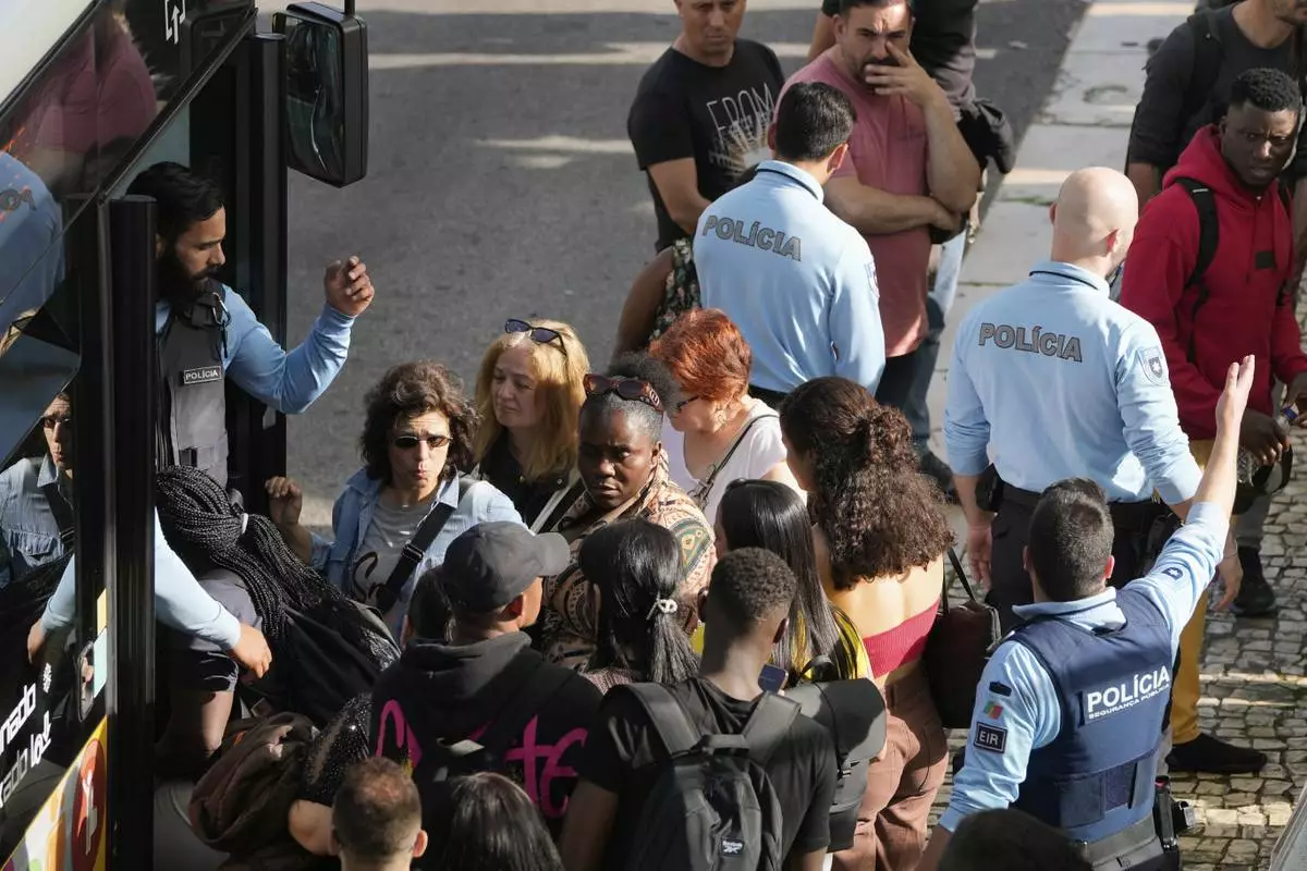 Police controls passengers trying to catch buses at Oriente transportation hub during a nationwide power outage that stopped trains and subway in Lisbon, Monday, April 28, 2025. (AP Photo/Armando Franca)