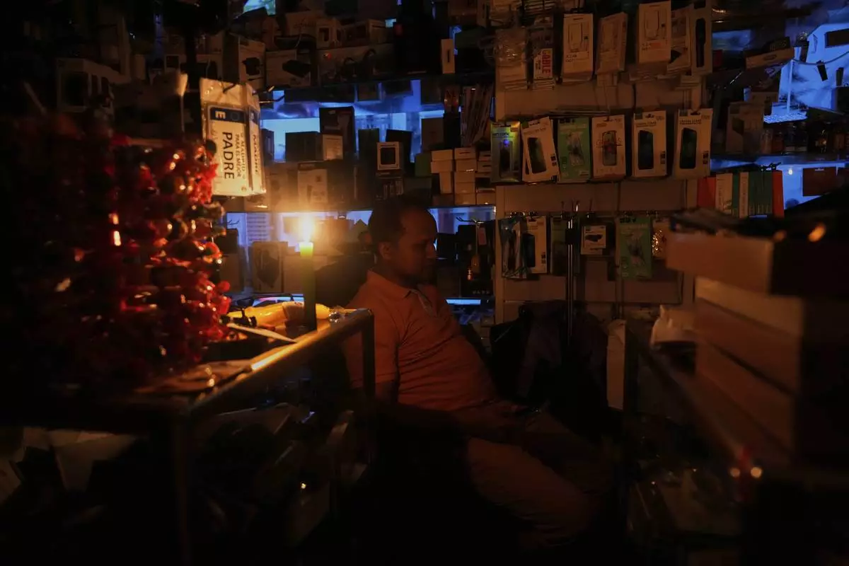 A vendor sits inside his shop during a major power outage, in Madrid, Monday, April 28, 2025. (AP Photo/Manu Fernandez)