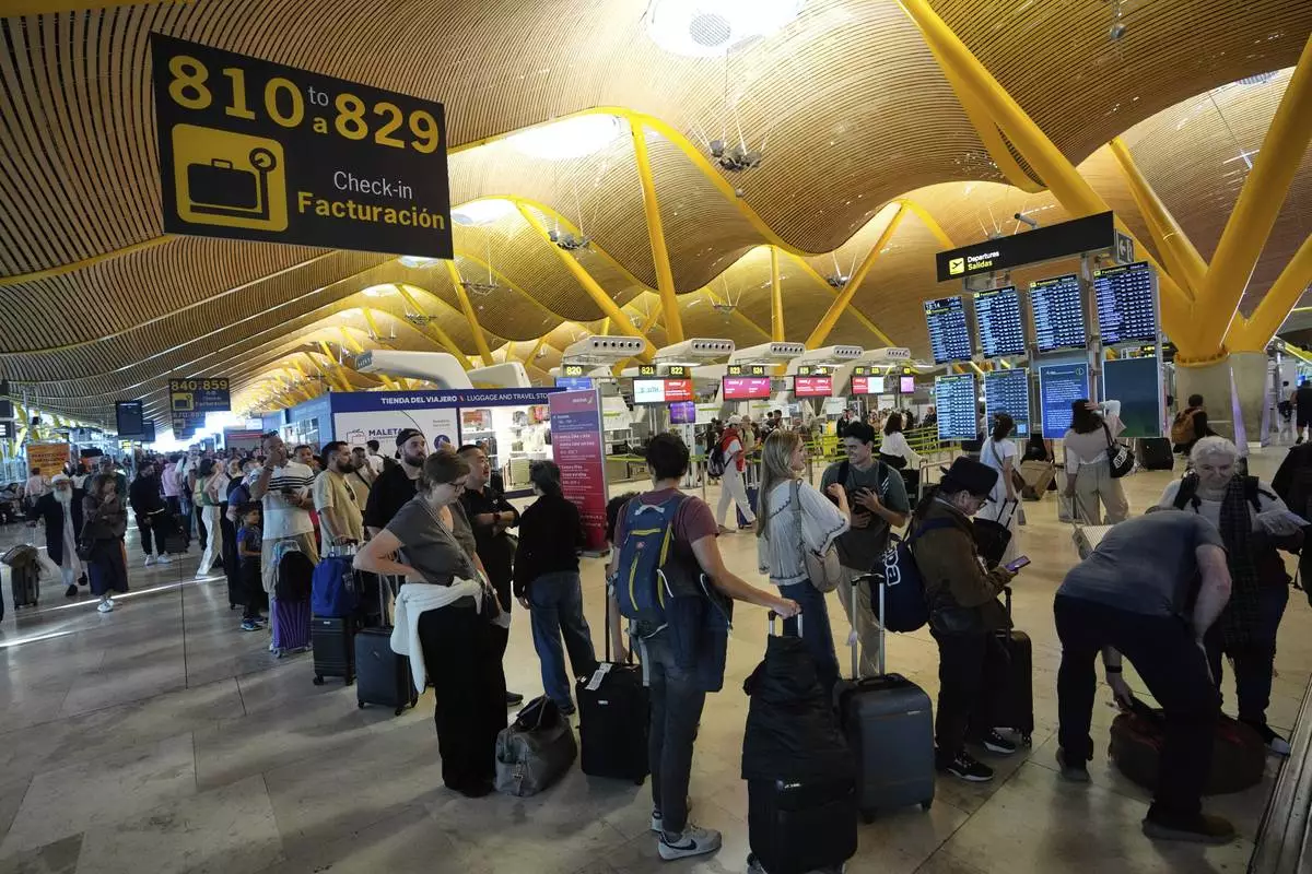 Passengers queue at Madrid airport, during a major power outage, Monday, April 28, 2025. (AP Photo/Manu Fernandez)