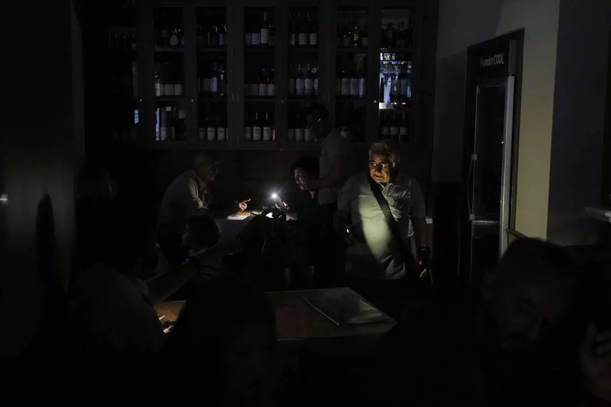 People eat inside a restaurant during a massive power outage in Madrid, Monday, April 28, 2025. (AP Photo/Manu Fernandez)