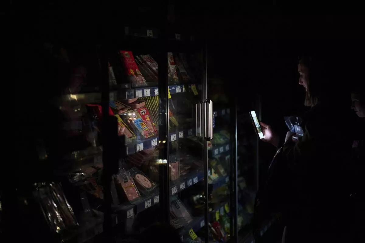 People buy food at a supermarket during a massive power outage in Pamplona, northern Spain, Monday, April 28, 2025. (AP Photo/Miguel Oses)