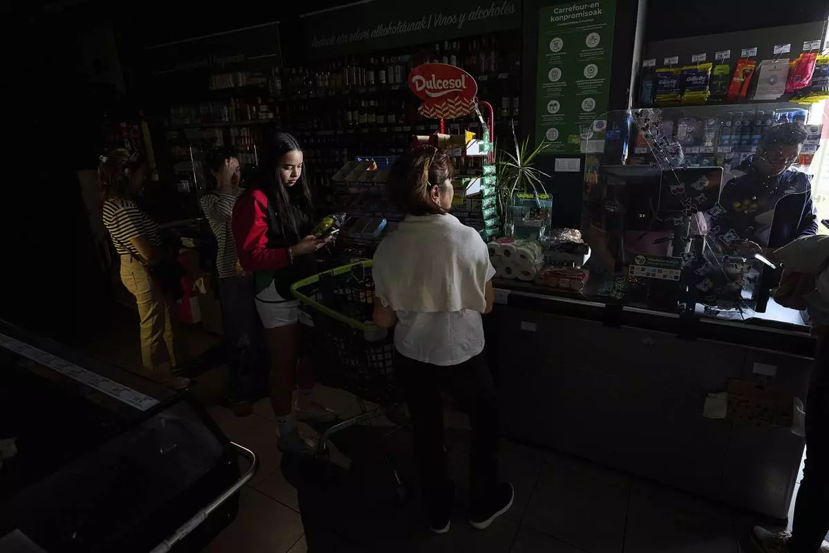 People buy food at a supermarket during a massive power outage in Pamplona, northern Spain, Monday, April 28, 2025. (AP Photo/Miguel Oses)
