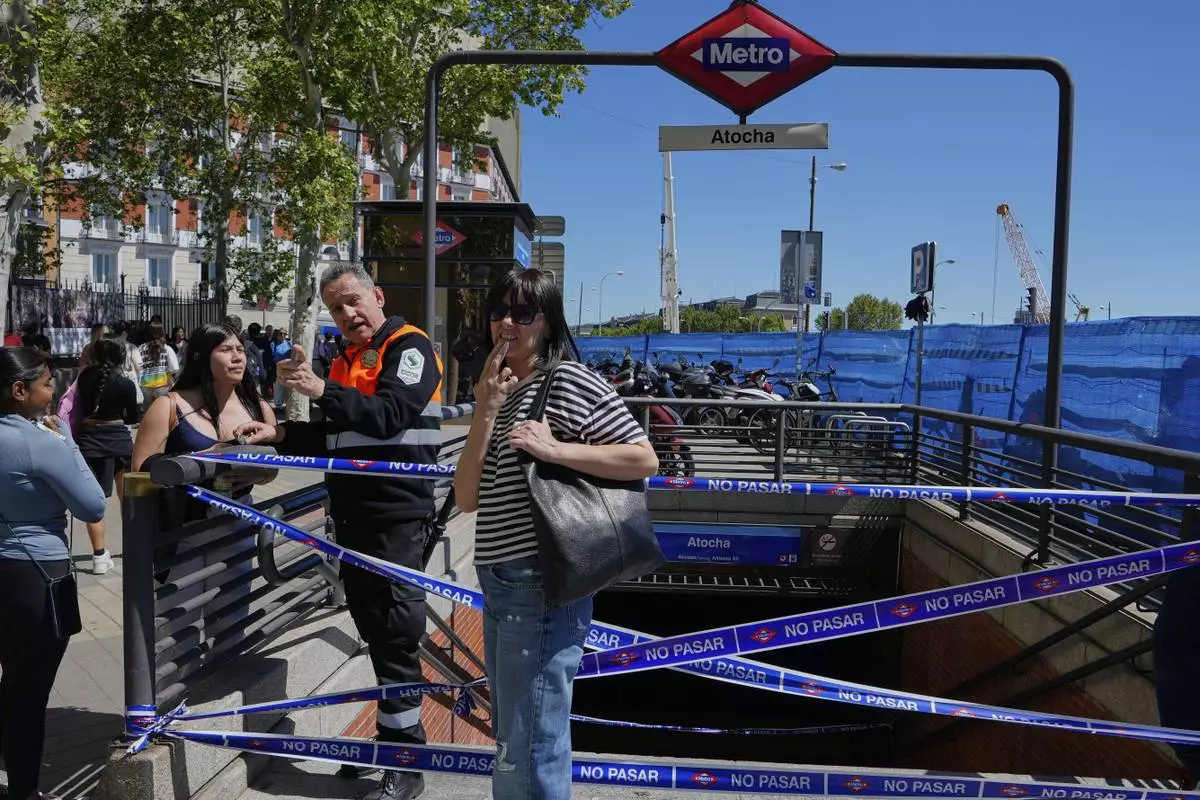 A security guard speaks with a woman outside a temporarily closed metro station during a nationwide power outage in Madrid, Monday, April 28, 2025. (AP Photo/Manu Fernandez)