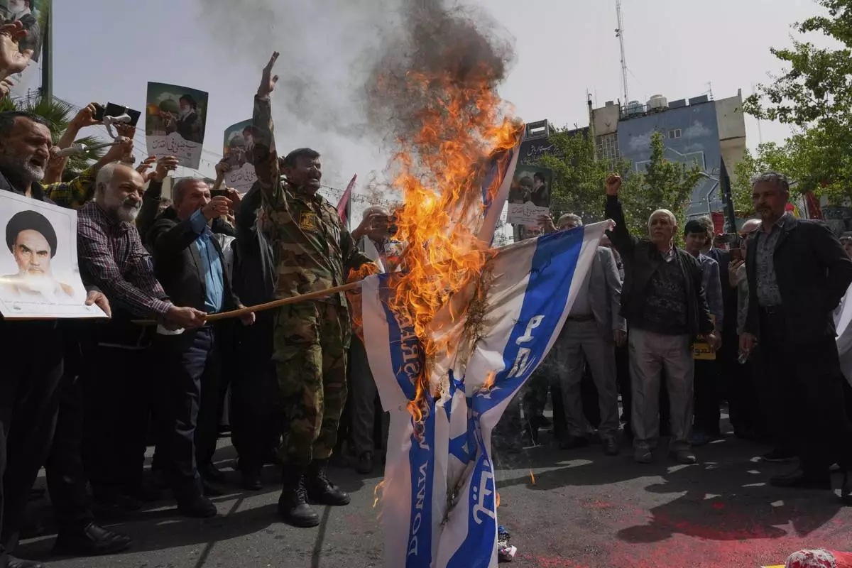Iranian protesters burn representations of the Israeli flag during a demonstration at the Felestin (Palestine) Sq. in Tehran, Iran, Wednesday, April 9, 2025. (AP Photo/Vahid Salemi)