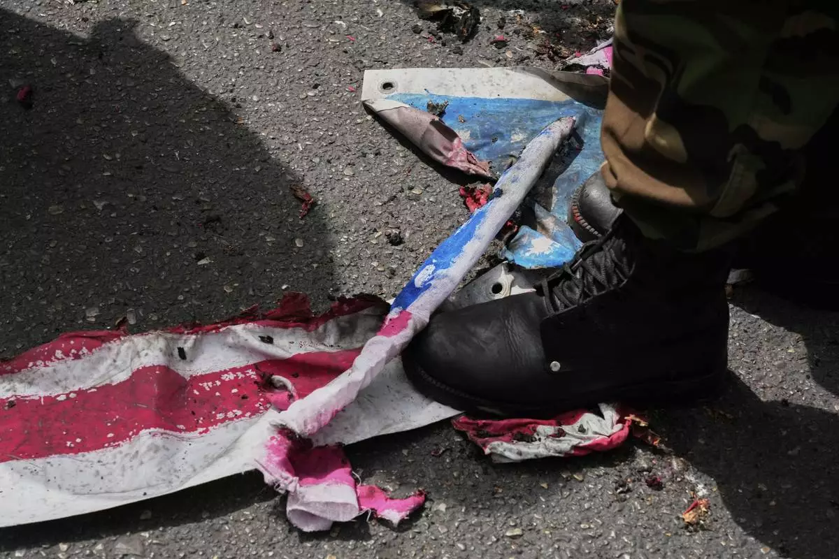 A member of the Iranian Basij paramilitary force tramples on a burnt representation of the U.S. flag during an anti-Israeli demonstration at the Felestin (Palestine) Sq. in Tehran, Iran, Wednesday, April 9, 2025. (AP Photo/Vahid Salemi)