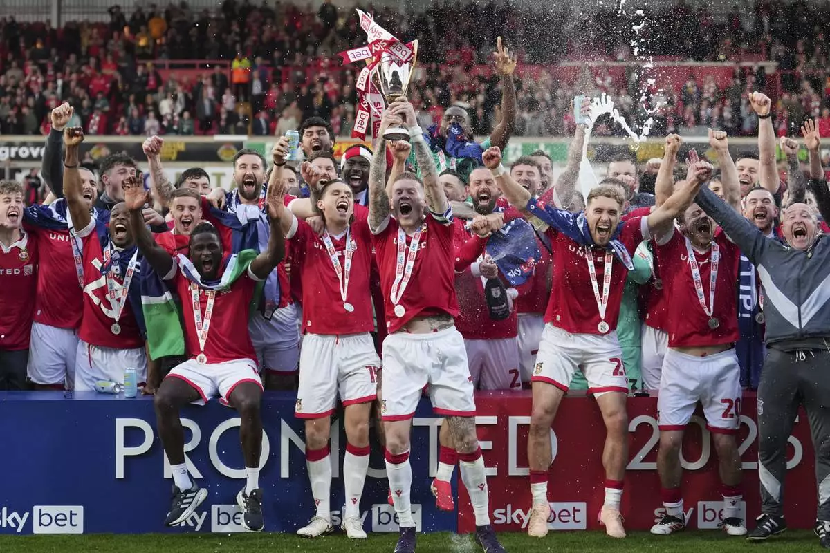 Wrexham players celebrate as they win the English League One soccer match between Wrexham and Charlton Athletic at the Racecourse ground in Wrexham, Wales, Saturday, April 26, 2025. (AP Photo/Jon Super)
