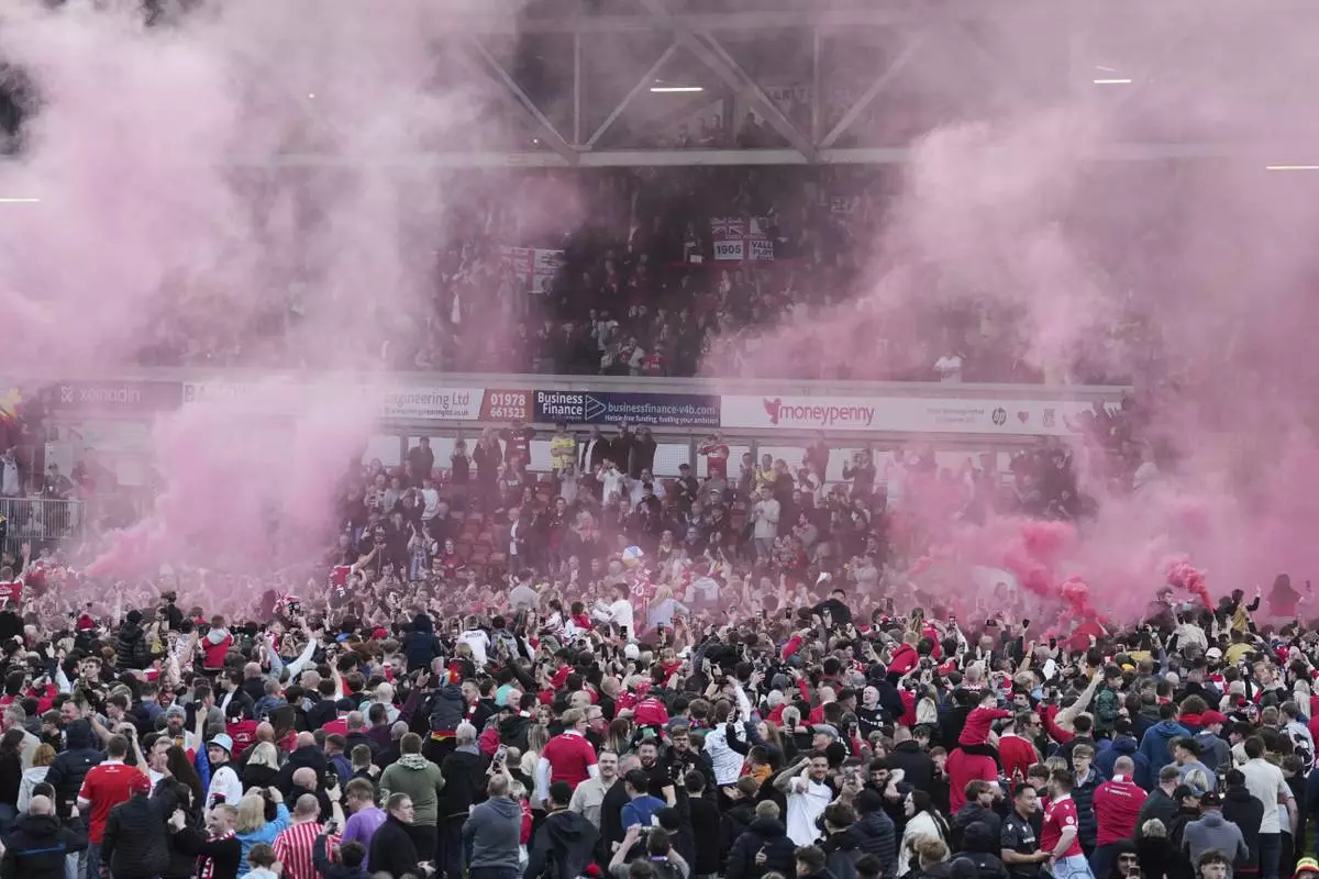 Wrexham players celebrate with fans as they win the English League One soccer match between Wrexham and Charlton Athletic at the Racecourse ground in Wrexham, Wales, Saturday, April 26, 2025. (AP Photo/Jon Super)