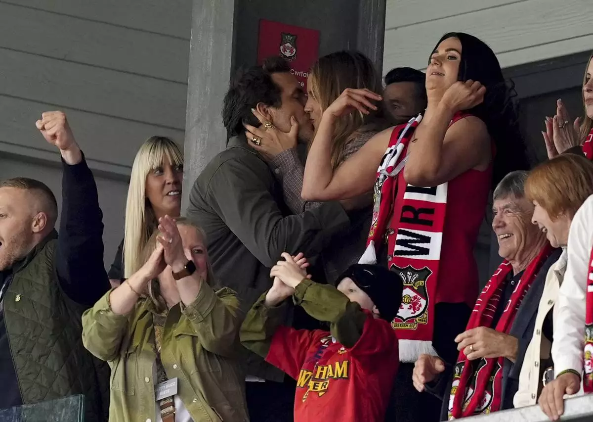 Wrexham co-owner Ryan Reynolds, top left, kisses his wife Blake Lively after Wrexham scored their first goal English League One soccer match between Wrexham and Charlton Athletic at the Racecourse ground in Wrexham, Wales, Saturday, April 26, 2025. (Martin Rickett/PA via AP)