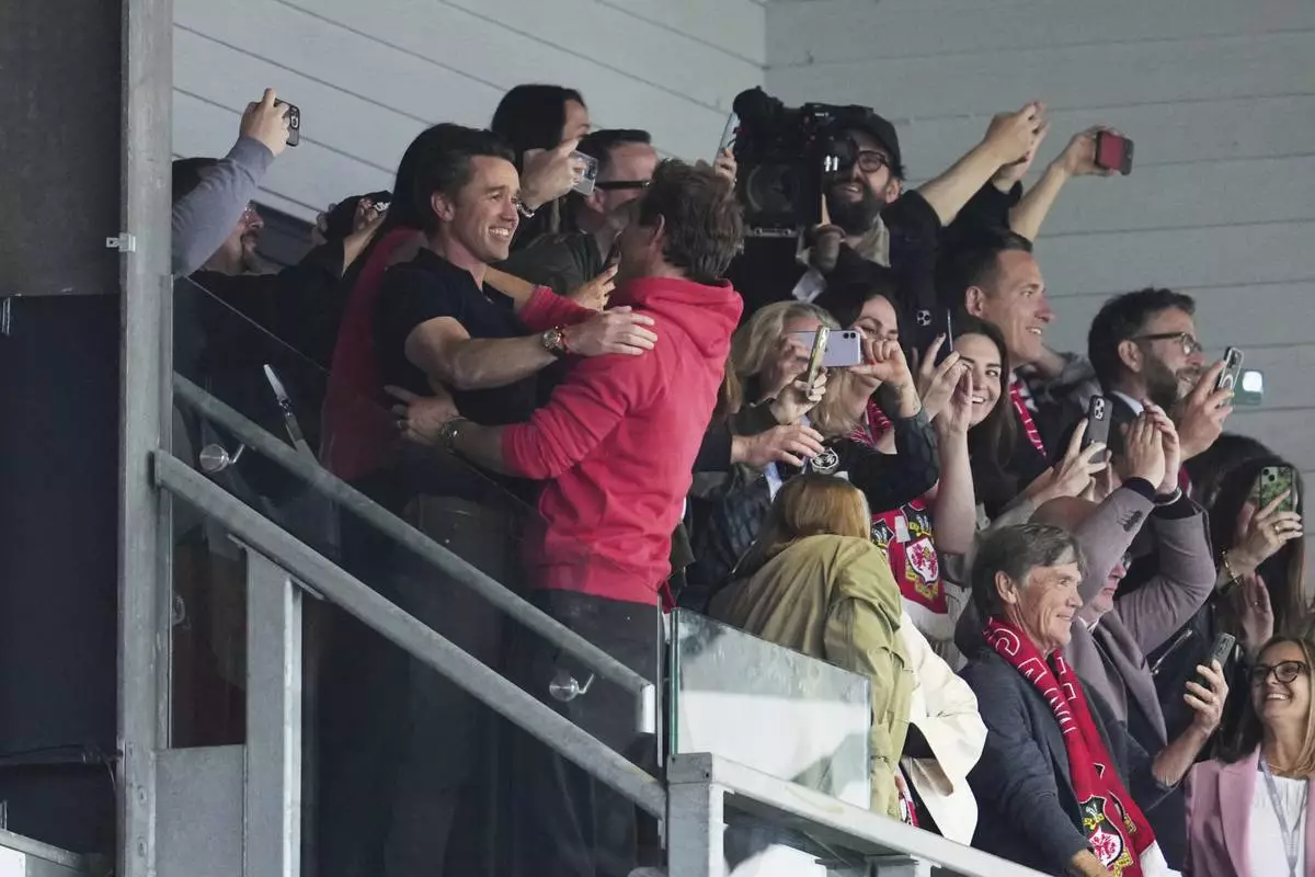 Wrexham co-owners Ryan Reynolds, center, and Rob McElhenney celebrate at the end of the English League One soccer match between Wrexham and Charlton Athletic at the Racecourse ground in Wrexham, Wales, Saturday, April 26, 2025. (AP Photo/Jon Super)
