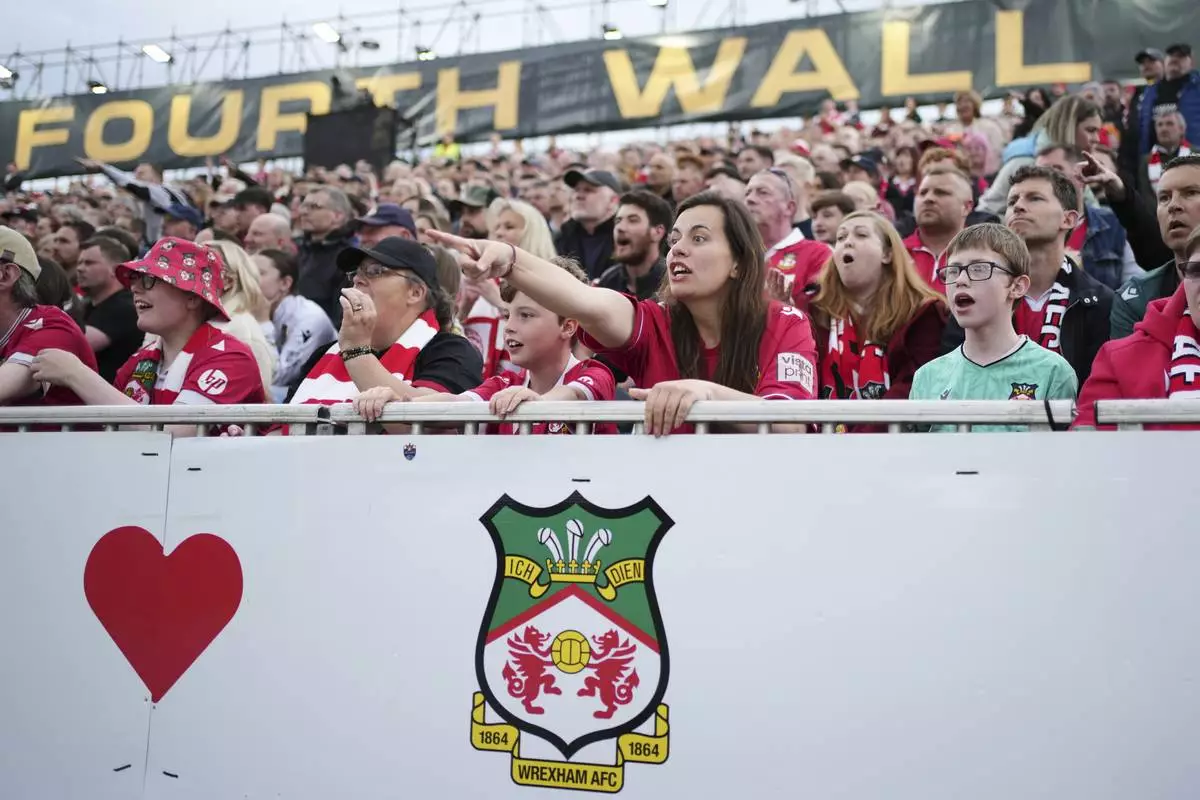 Wrexham fans watch the English League One soccer match between Wrexham and Charlton Athletic at the Racecourse ground in Wrexham, Wales, Saturday, April 26, 2025. (AP Photo/Jon Super)