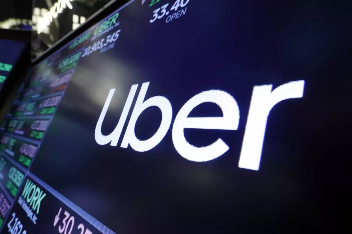 FILE - The Uber logo appears above a trading post on the floor of the New York Stock Exchange, Aug. 16, 2019. (AP Photo/Richard Drew, File)
