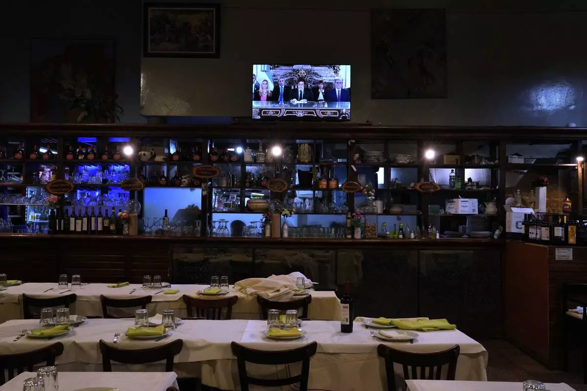 A television airs a national message by President Javier Milei, accompanied by members of his Cabinet, at a restaurant in Buenos Aires, Argentina, Friday, April 11, 2025. (AP Photo/Natacha Pisarenko)