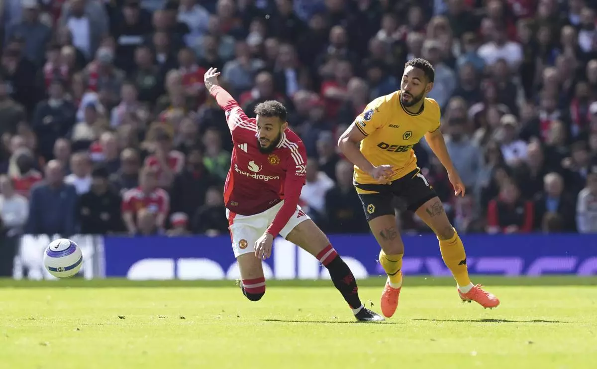 Manchester United's Noussair Mazraoui, left and Wolverhampton Wanderers' Matheus Cunha vie for the ball, during the English Premier League soccer match between Manchester United and Wolverhampton Wanderers, at Old Trafford, Manchester, England, Sunday, April 20, 2025. (Martin Rickett/PA via AP)