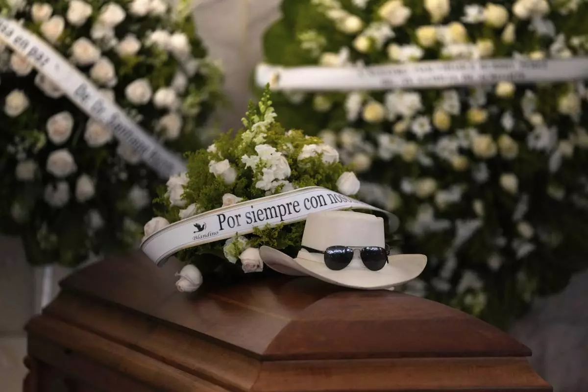 The hat and sunglasses of Dominican singer Rubby Perez, who died in the roof collapse at the Jet Set nightclub during his merengue concert, sit on his casket during his wake at the Eduardo Brito National Theater in Santo Domingo, Dominican Republic, Thursday, April 10, 2025. (AP Photo/Matias Delacroix)