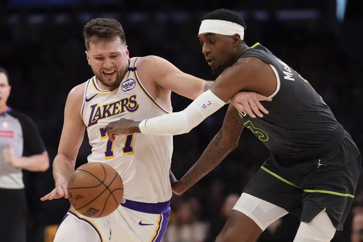 Minnesota Timberwolves forward Jaden McDaniels, right, reaches in on Los Angeles Lakers guard Luka Doncic during the first half in Game 1 of an NBA first-round playoff series Saturday, April 19, 2025, in Los Angeles. (AP Photo/Mark J. Terrill)