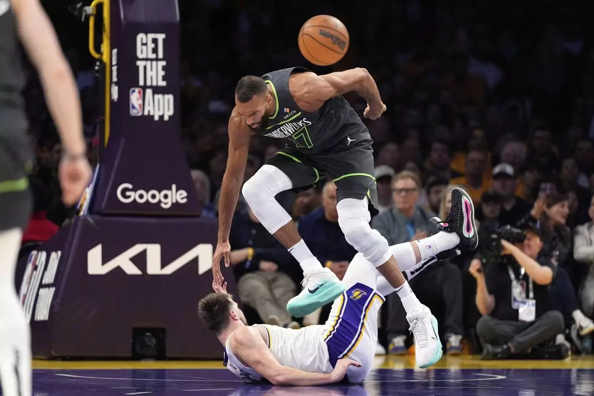 Minnesota Timberwolves center Rudy Gobert, top, trips over Los Angeles Lakers guard Luka Doncic during the first half in Game 1 of an NBA first-round playoff series Saturday, April 19, 2025, in Los Angeles. (AP Photo/Mark J. Terrill)
