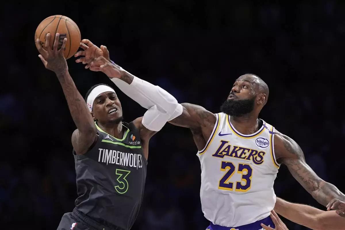 Minnesota Timberwolves forward Jaden McDaniels, left, and Los Angeles Lakers forward LeBron James grapple for the ball during the first half in Game 1 of an NBA first-round playoff series Saturday, April 19, 2025, in Los Angeles. (AP Photo/Mark J. Terrill)