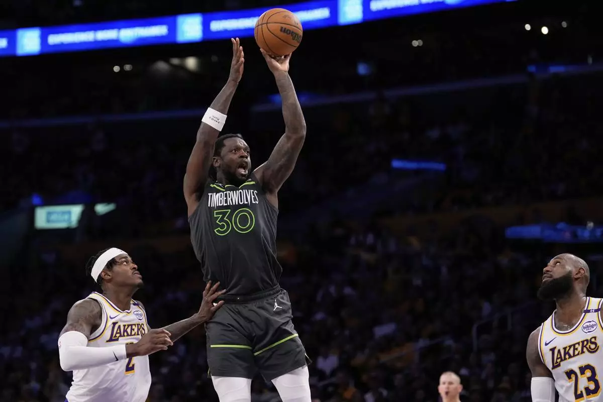 Minnesota Timberwolves forward Julius Randle, center, shoots as Los Angeles Lakers forward Jarred Vanderbilt, left, and forward LeBron James defend during the second half in Game 1 of an NBA first-round playoff series Saturday, April 19, 2025, in Los Angeles. (AP Photo/Mark J. Terrill)