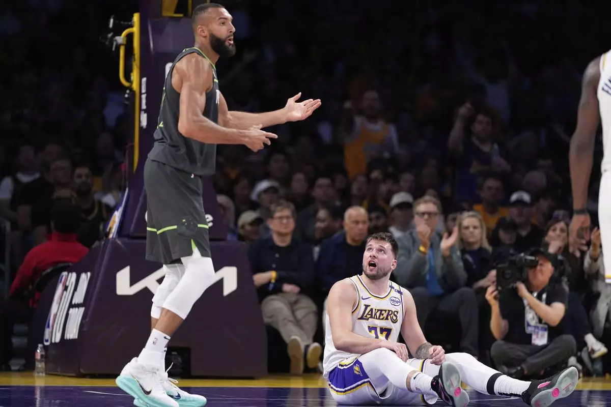 Minnesota Timberwolves center Rudy Gobert, left, gestures as Los Angeles Lakers guard Luka Doncic talks to him after Gobert tripped over Doncic during the first half in Game 1 of an NBA first-round playoff series Saturday, April 19, 2025, in Los Angeles. (AP Photo/Mark J. Terrill)