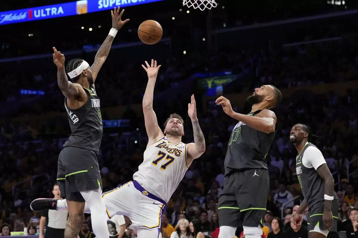 Los Angeles Lakers guard Luka Doncic (77) shoots as Minnesota Timberwolves guard Nickeil Alexander-Walker (9), center Rudy Gobert and center Naz Reid defend during the first half in Game 1 of an NBA first-round playoff series Saturday, April 19, 2025, in Los Angeles. (AP Photo/Mark J. Terrill)