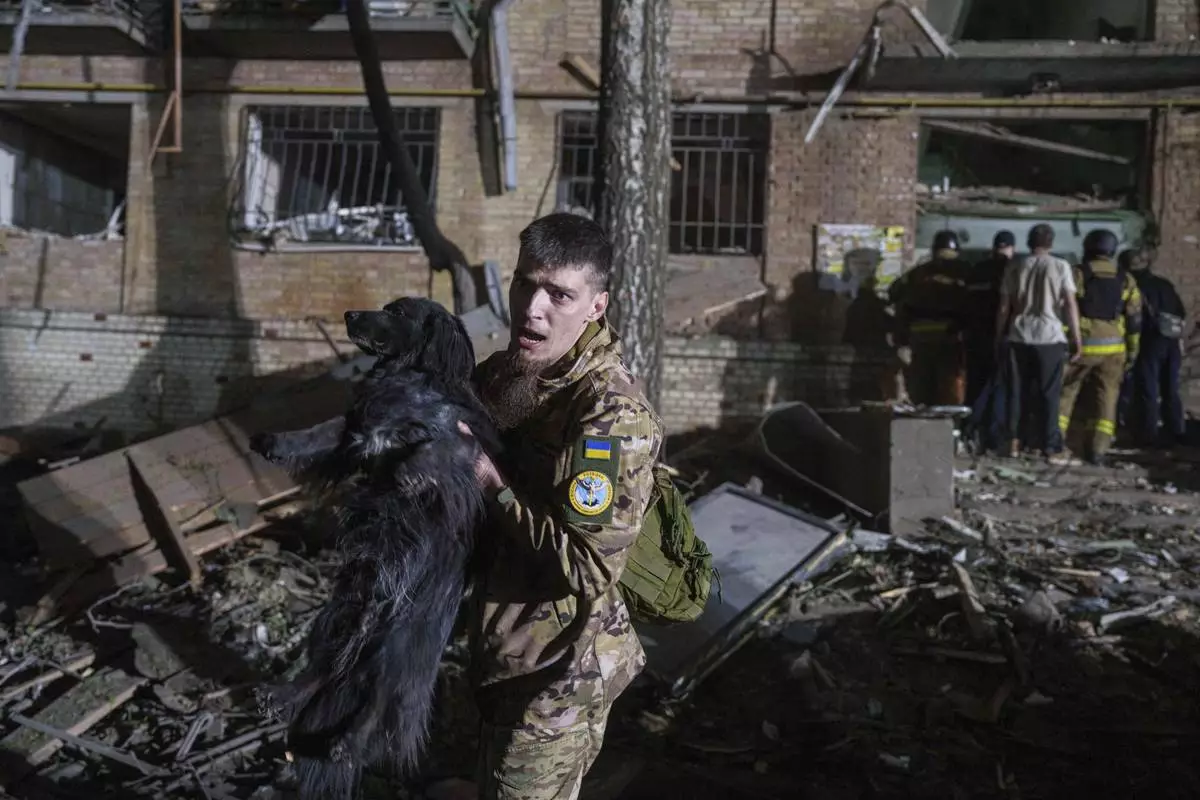 A Ukrainian serviceman carries a dog out of a house damaged by a Russian airstrike in a residential neighborhood in Kyiv, Ukraine, on Thursday, April 24, 2025. (AP Photo/Evgeniy Maloletka)