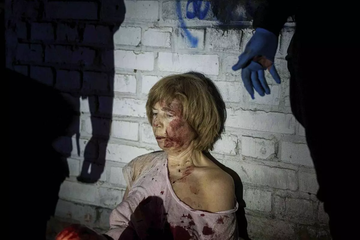 An injured woman sits near her house, which was damaged by a Russian airstrike, in a residential neighbourhood in Kyiv, Ukraine, on Thursday, April 24, 2025. (AP Photo/Evgeniy Maloletka)