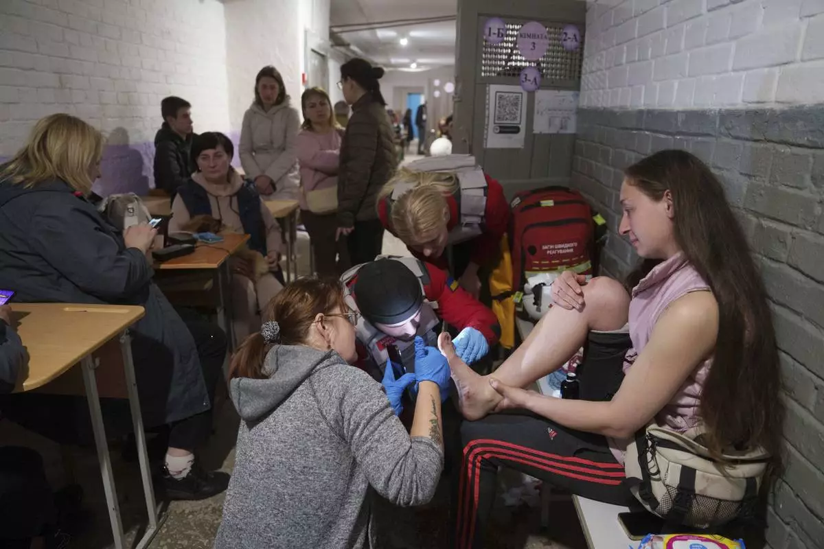 Medics treat an injured woman in a school basement being used as a shelter after a Russian airstrike on a residential neighborhood in Kyiv, Ukraine, on Thursday, April 24, 2025. (AP Photo/Evgeniy Maloletka)