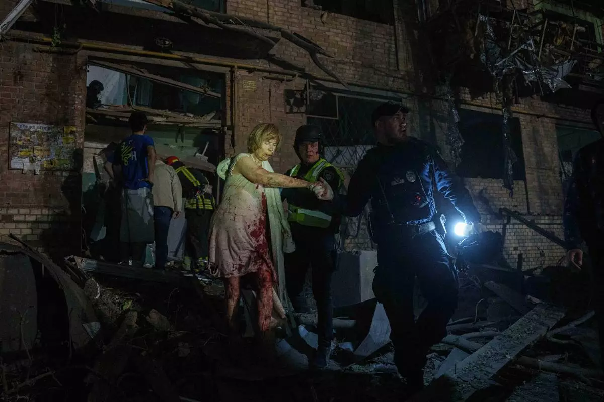 Police officers guide an injured woman out of her house, which was damaged by a Russian airstrike, in a residential neighbourhood in Kyiv, Ukraine, on Thursday, April 24, 2025. (AP Photo/Evgeniy Maloletka)