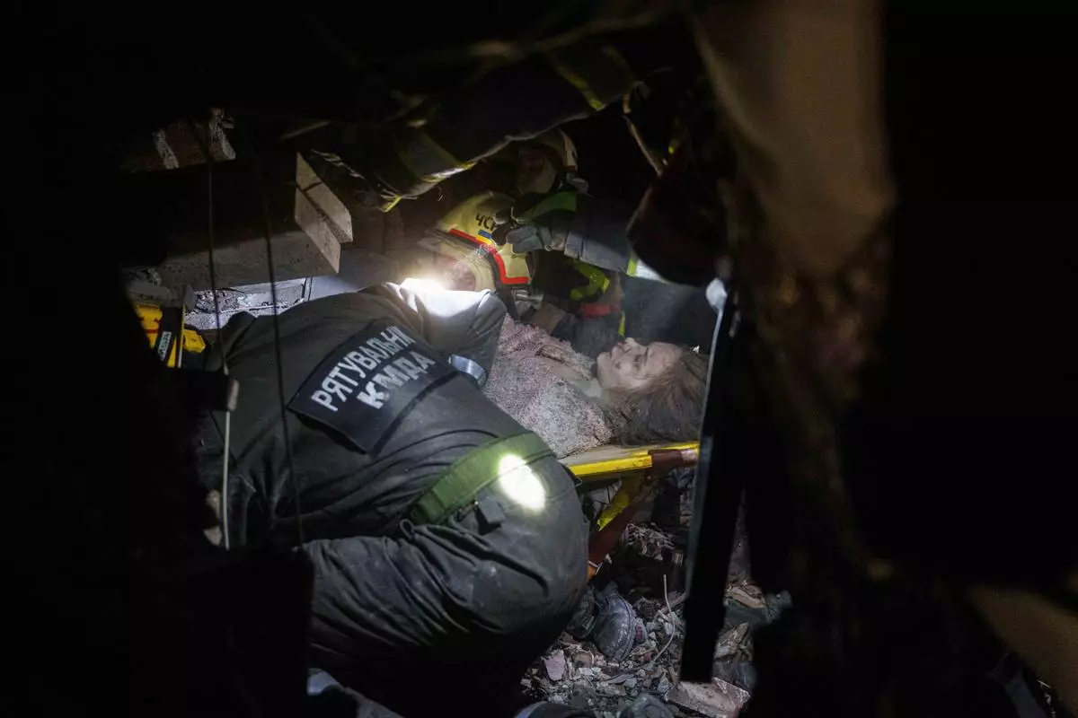 Rescue workers evacuate an injured woman from the rubble of a house destroyed by a Russian airstrike in a residential neighborhood in Kyiv, Ukraine, on Thursday, April 24, 2025. (AP Photo/Evgeniy Maloletka)