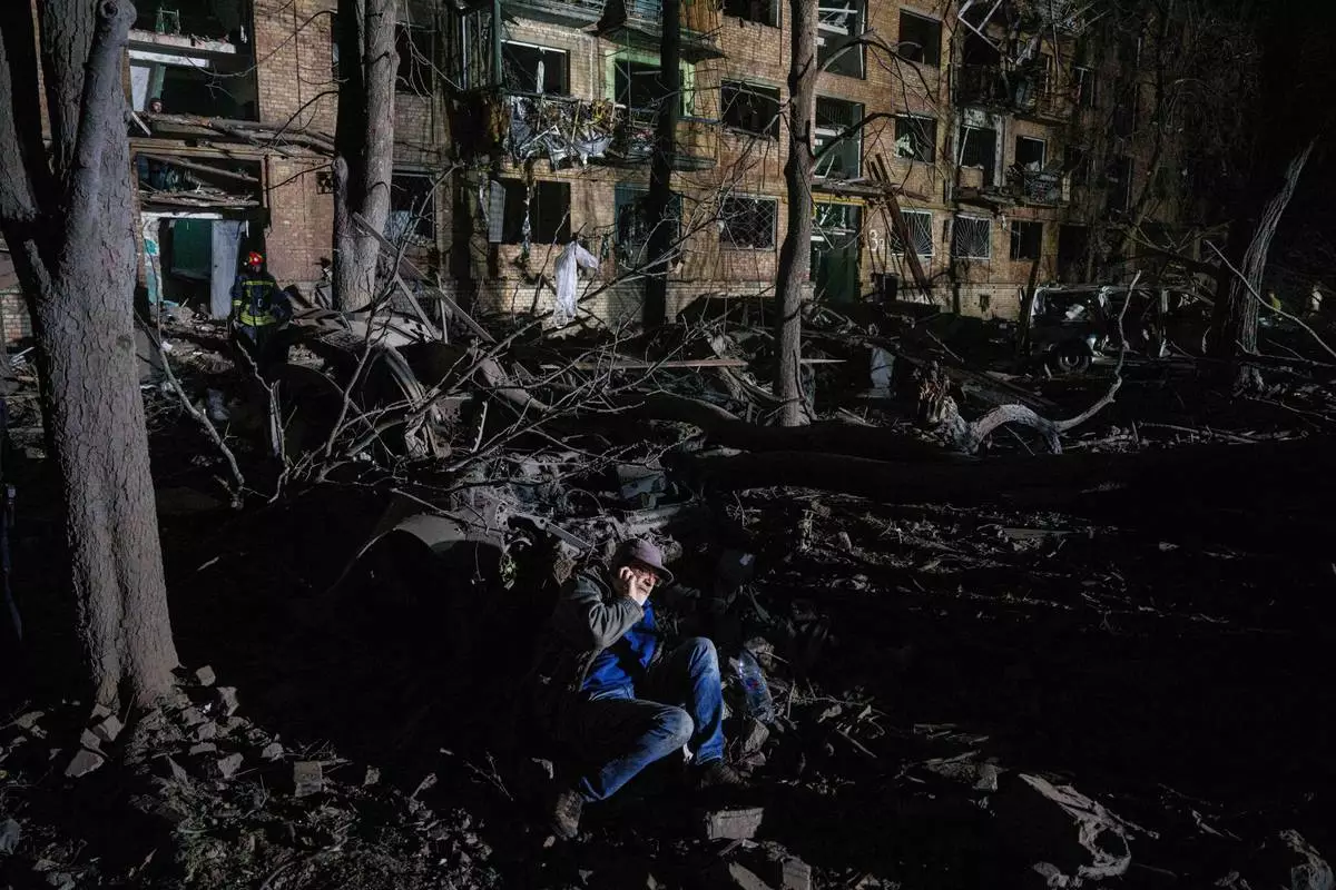 A man sits on the ground outside of a house damaged by a Russian airstrike in a residential neighborhood in Kyiv, Ukraine, on Thursday, April 24, 2025. (AP Photo/Evgeniy Maloletka)