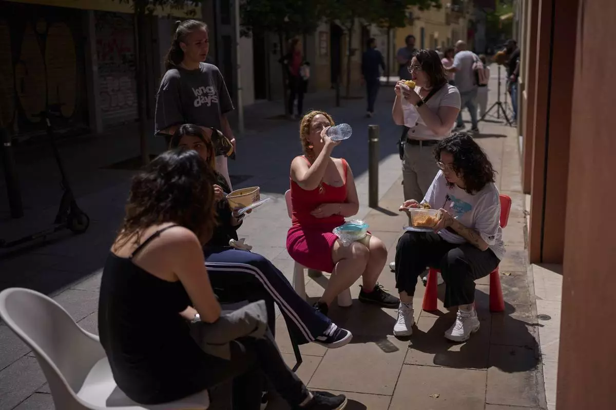 Employees of a shop have their lunch, during a major power outage in Barcelona, Spain, Monday, April 28, 2025. (AP Photo/Emilio Morenatti)