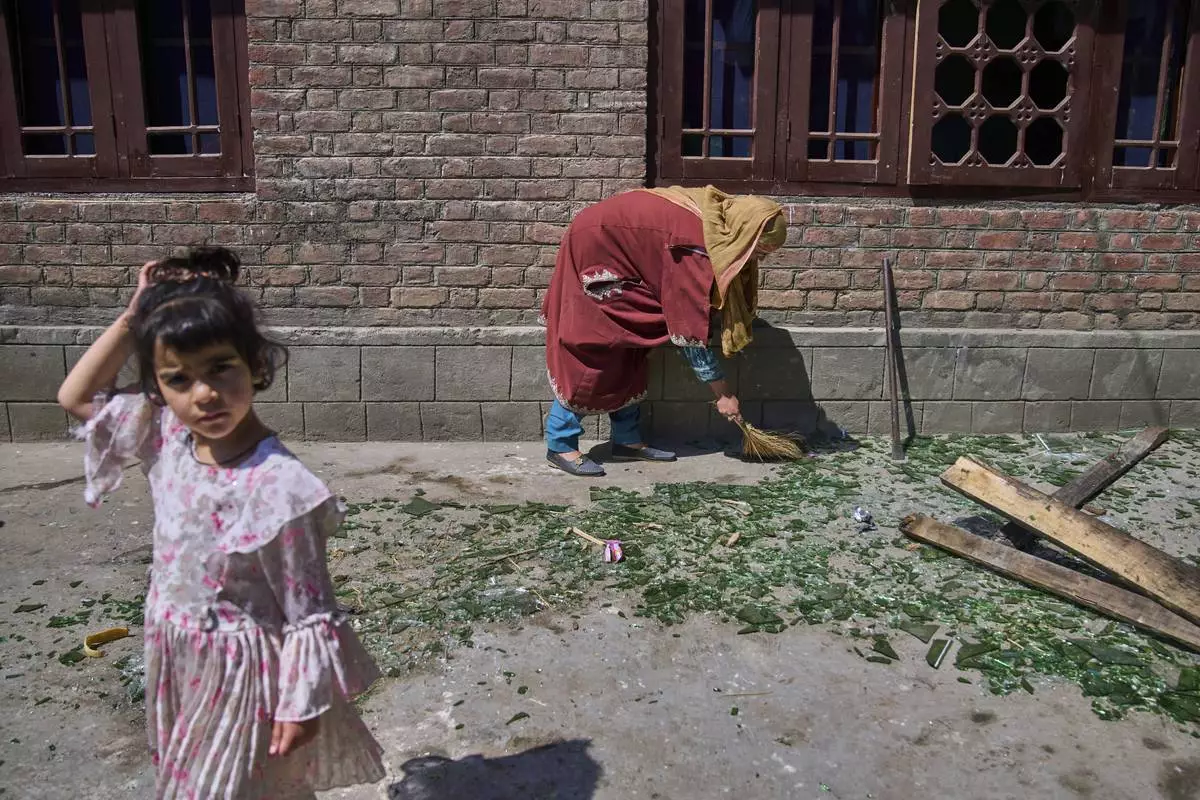 A Kashmiri woman clears shattered glass outside her home after it was damaged in a blast at the house of Asif Sheikh, who officials say is a militant and have blamed for involvement in the deadly attack on tourists in Pahalgam, at Monghama village in Tral, south of Srinagar, Indian controlled Kashmir, Friday, April 25, 2025. (AP Photo/Dar Yasin)