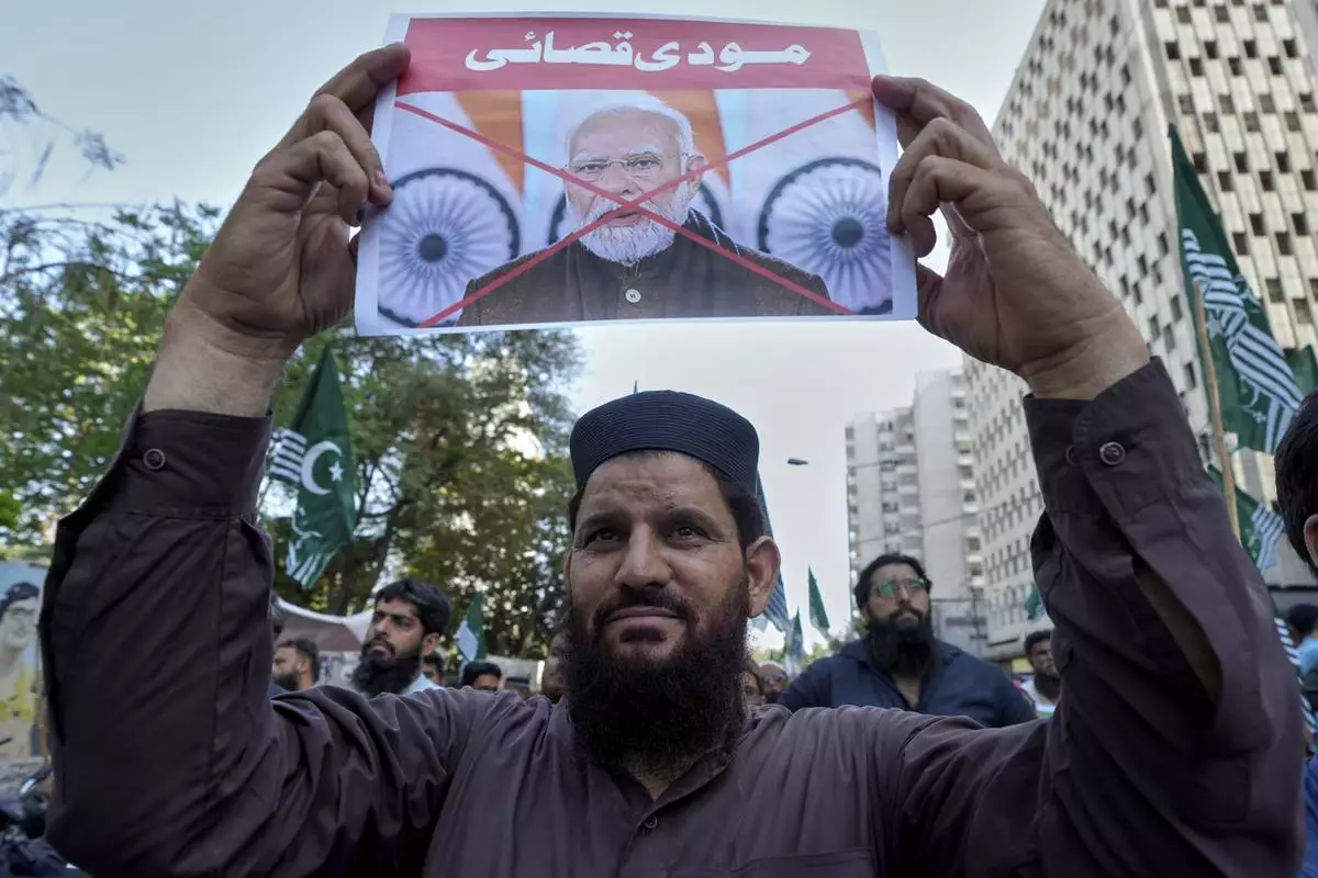 A supporter of the Pakistan Murkazi Muslim League party holds a crossed poster of Indian Prime Minister Narendra Modi with the words 'Modi butcher" during a demonstration against the suspension of water-sharing treaty by India with Pakistan, in Karachi, Pakistan Thursday, April 24, 2025. (AP Photo/Fareed Khan)